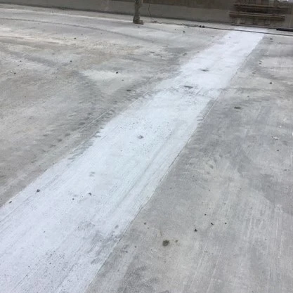 A close-up image of a concrete link slab covering a bridge deck joint after finishing is completed.